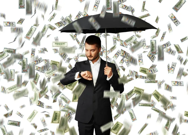 Homem sob chuva dinheiro olhando para assistir — Fotografia de Stock