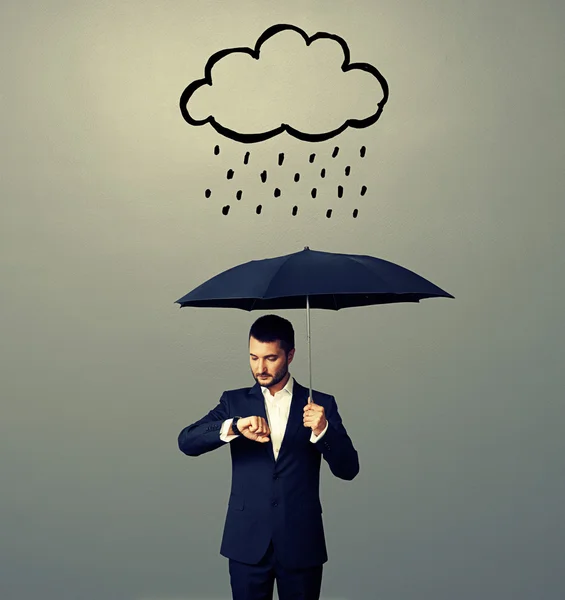 Homem com guarda-chuva olhando para relógio — Fotografia de Stock