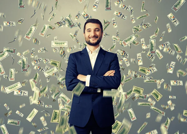 Улыбающийся бизнесмен под дождем доллара — стоковое фото