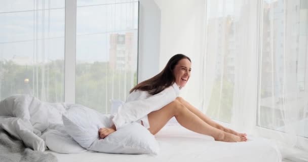 Mujer despreocupada arrojando almohada mientras se relaja en la cama — Vídeo de stock