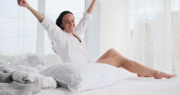 Hermosa joven mujer abrazando almohada mientras está acostada en la cama — Vídeo de stock