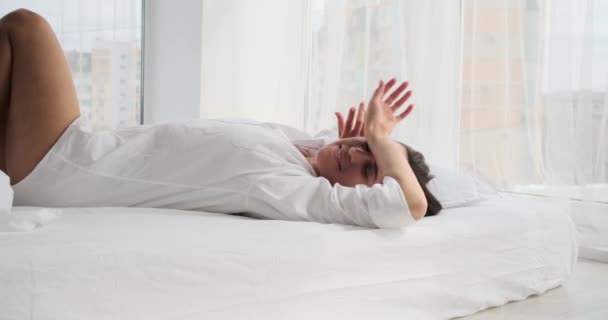 Счастливая молодая женщина, лежащая на кровати — стоковое видео