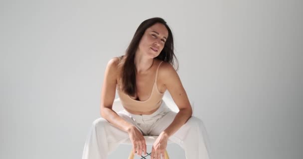 Vacker ung kvinna poserar sittande på stol — Stockvideo
