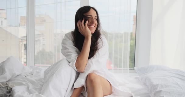 Mooie vrouw lachend zittend op bed — Stockvideo