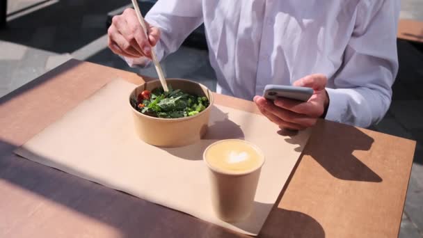 昼ご飯を食べながら携帯電話を使う男の真ん中 — ストック動画