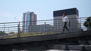 İş adamı yokuşta yürürken cep telefonuyla konuşuyor.