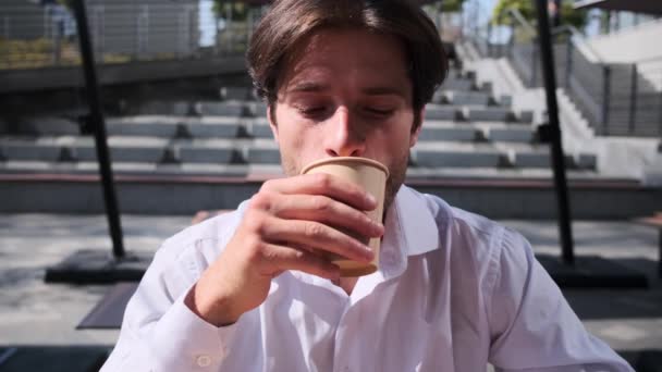 A fiatalember kávét iszik és mosolyog. — Stock videók