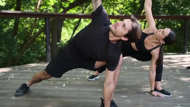 Par som övar roterande lunge och halvmåne-lunge-yoga poserar — Stockvideo