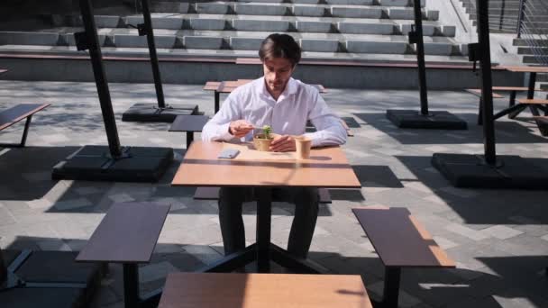 Young businessman eating salad for lunch — Stock Video