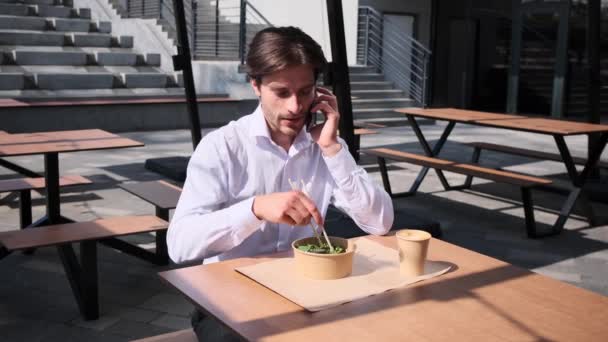 사업가가 점심을 먹으면서 휴대 전화로 이야기하는 모습 — 비디오