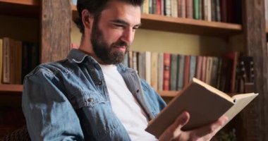 Evde kitap okuyan bir adam.