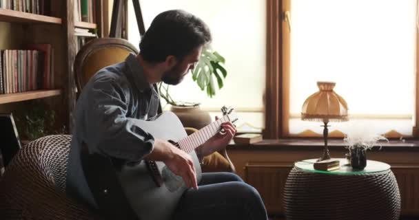 Мужчина играет на гитаре дома — стоковое видео