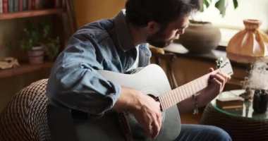 Evde gitar çalan adam.