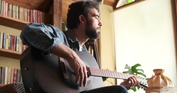 Man sjunger sång och spelar gitarr hemma — Stockvideo