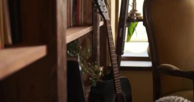 Gitar ahşap kitaplığa yaslanıyor.