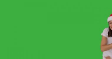 Noel Baba şapkalı neşeli kadın yeşil arka planda dans ediyor.