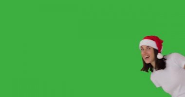 Noel Baba şapkalı kadın yeşil ekranda selam veriyor.