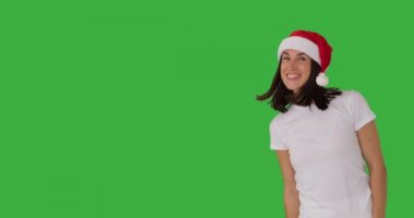 Noel Baba şapkalı kadın yeşil ekranda selam veriyor.