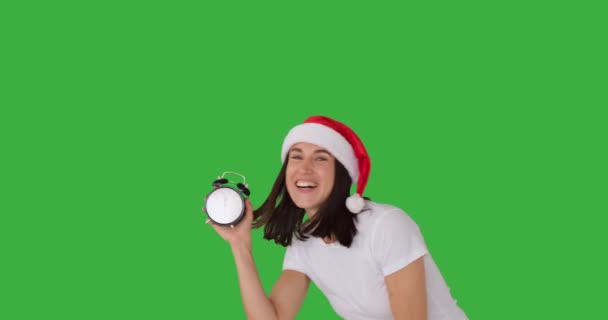 Begeisterte Frau mit Weihnachtsmann-Hut zeigt Zeit auf dem Wecker — Stockvideo