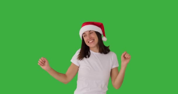 Frau mit Weihnachtsmütze tanzt über grünem Hintergrund — Stockvideo