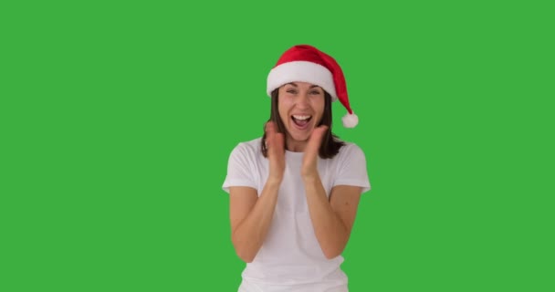 Aufgeregte Frau mit Weihnachtsmütze klatscht Hände über grünem Hintergrund — Stockvideo