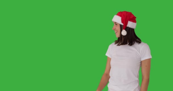 Kvinna i röd Santa hatt pekar över grön bakgrund — Stockvideo