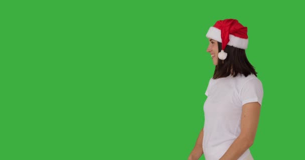Žena v červeném santa klobouk ukazující prst přes zelené pozadí — Stock video