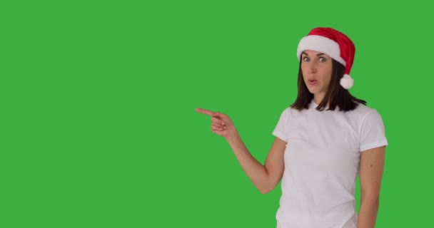 Fantastisk kvinna i röd Santa hatt pekar över grön bakgrund — Stockvideo