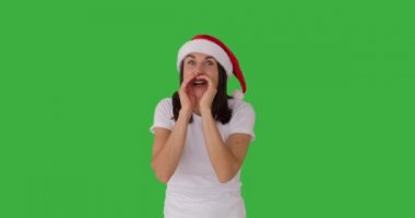 Noel Baba şapkalı neşeli kadın yeşil ekranda gizli şeyler fısıldıyor.