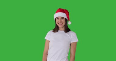 Yeşil arka planda Noel Baba şapkalı mutlu kadın. 