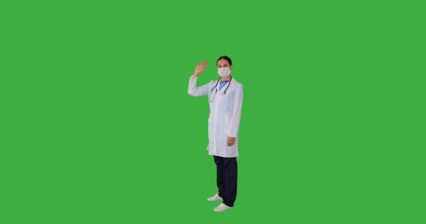 Женщина-врач в медицинской маске для лица и жестом прощаясь, машет рукой — стоковое видео