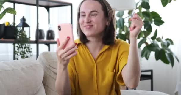 Женщина щелкает пальцами и слушает музыку на мобильном телефоне — стоковое видео