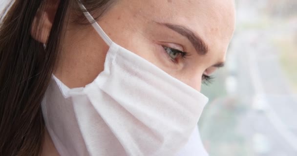 Mujer auto aislada con máscara facial protectora y mirando por la ventana de la casa — Vídeos de Stock