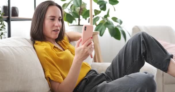 Mulher vídeo conversando usando telefone celular no sofá em casa — Vídeo de Stock