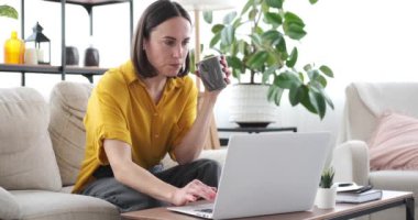 Evde çalışırken kahve içen bir kadın.