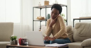 Dizüstü bilgisayar kullanan ve cep telefonuyla konuşan kadın.