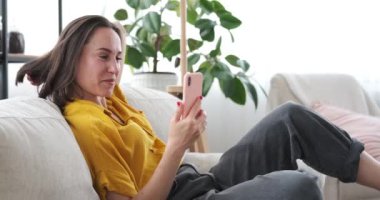 Evdeki koltukta cep telefonu kullanan bir kadının görüntülü sohbeti.