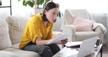 Dizüstü bilgisayar kullanan ve evrak işi yapan bir kadın.