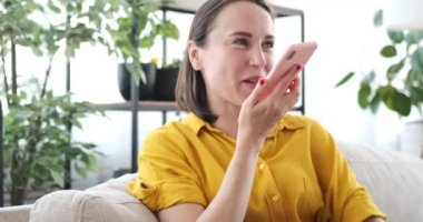 Evde cep telefonu kullanan bir kadın sesli mesaj kaydediyor.