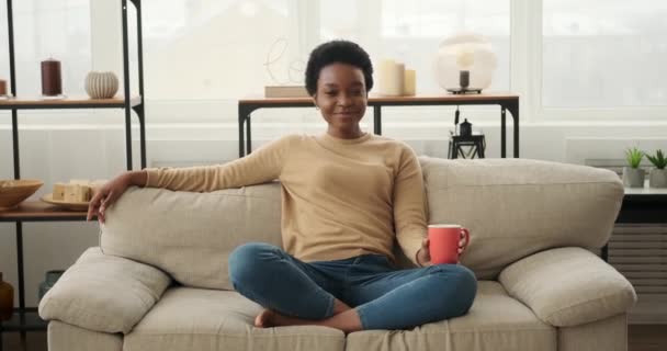 Tevreden vrouw zitten op de bank en het drinken van koffie — Stockvideo
