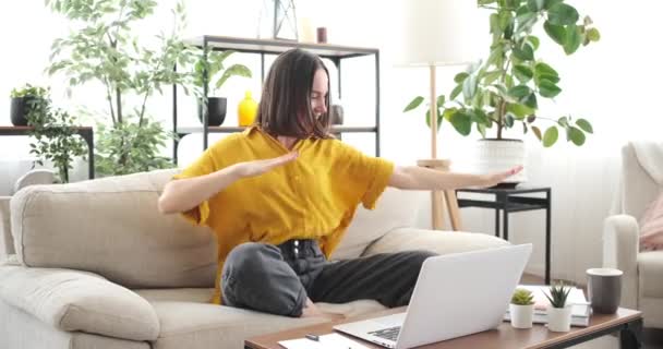 Ενθουσιασμένη γυναίκα χορεύει στον καναπέ ενώ εργάζεται από το σπίτι — Αρχείο Βίντεο