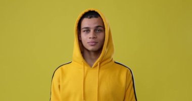 Sarı arka planda kapüşonlu adam.