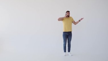Genç adam cep telefonuyla konuşurken yürüyor.