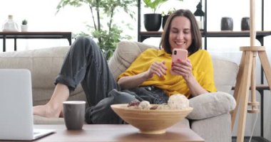 Kadın evde cep telefonu kullanarak selfie çekiyor.