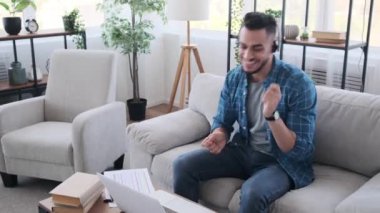 Genç işadamı müzik dinliyor ve dizüstü bilgisayarda çalışırken eğleniyor.