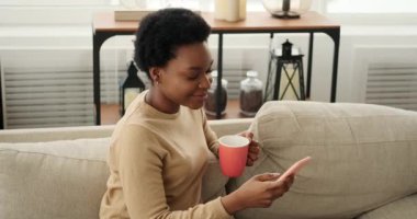 Kadın cep telefonu kullanıyor ve kahve içiyor.