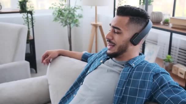 Šťastný muž poslouchá hudbu na sluchátkách doma — Stock video