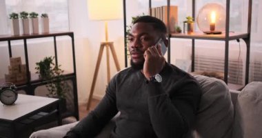 Ciddi bir genç adam cep telefonuyla konuşuyor.