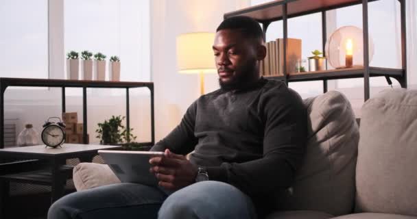 Muž sedí na pohovce a používá digitální tablet — Stock video