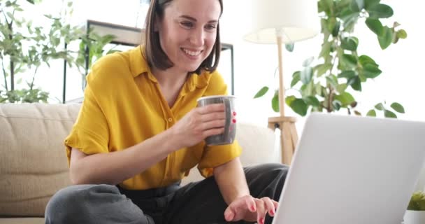 Γυναίκα πίνοντας καφέ και χρησιμοποιώντας το φορητό υπολογιστή στο σπίτι — Αρχείο Βίντεο